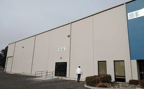 Tan tilt-up concrete warehouse with a flat roofline and a will-call entrance