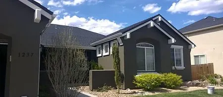 Single-storey stucco home painted charcoal grey with crisp white trim and fascia